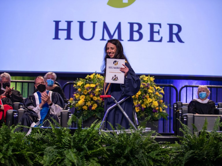 graduate holding up diploma as they exit stage