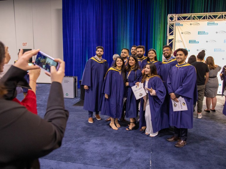 Person takes a cell phone photo of graduates