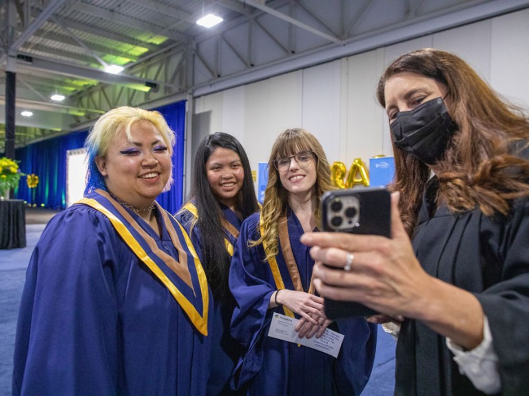 graduates look at a photo on person's phone