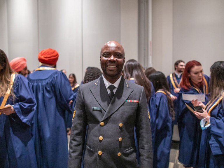 graduate in uniform smiling among crowd
