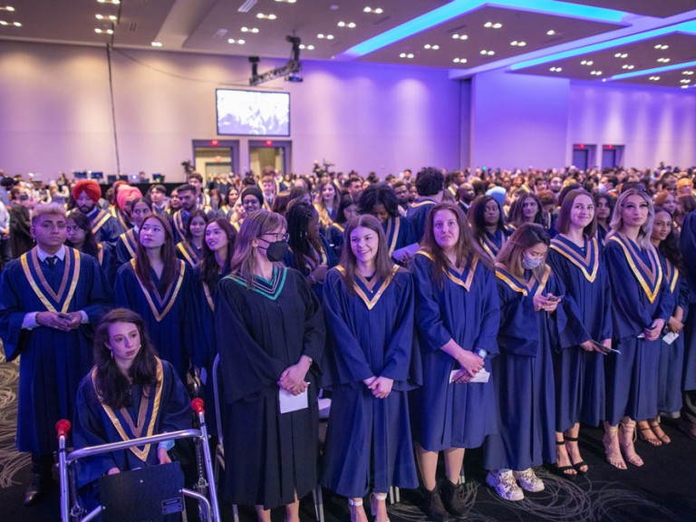 Humber graduates standing in front of their seats