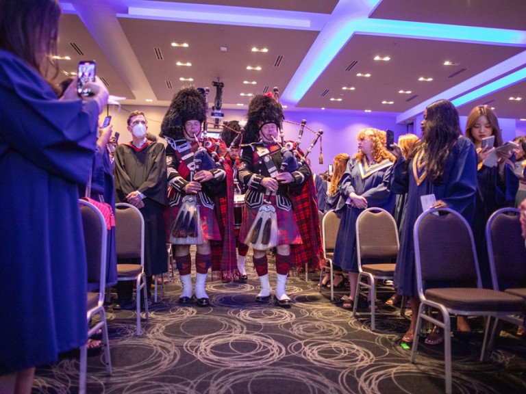 Bagpipe players in Scottish formalwear proceed down aisle