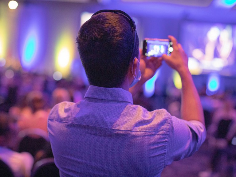 Person in audience taking photos of new graduates