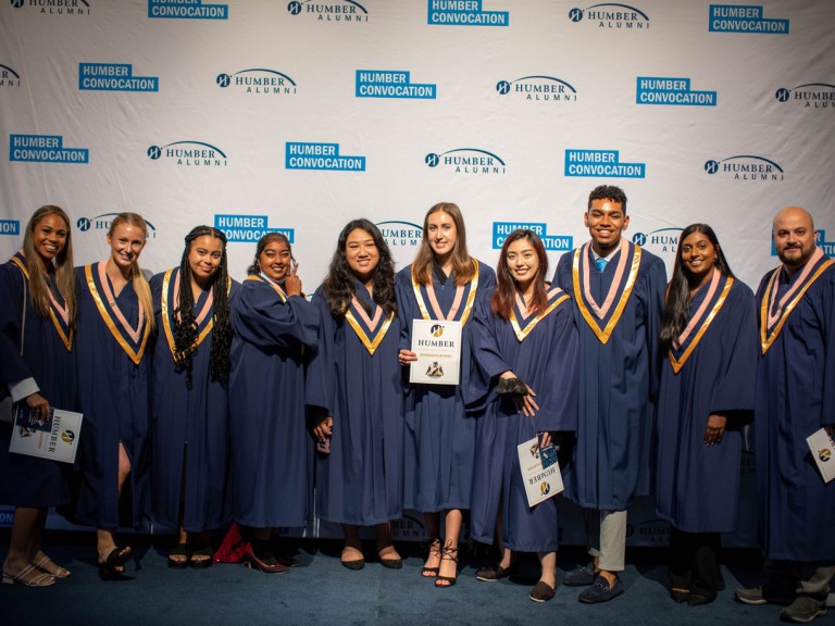 graduates in front of Humber Convocation wall
