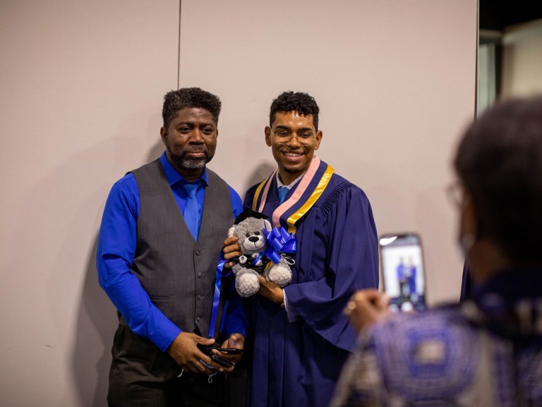 Graduate holding a teddy bear posing with parent 