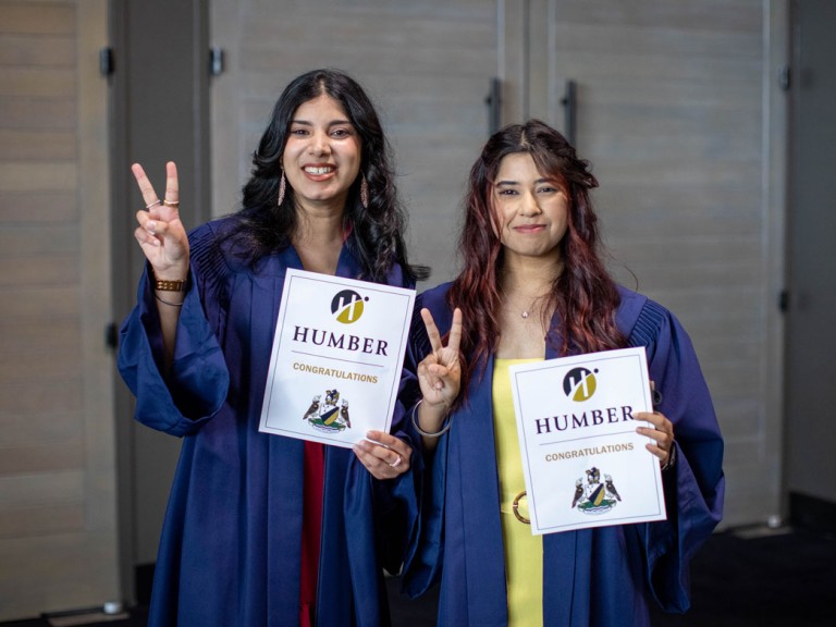 Two graduates holding up peace signs