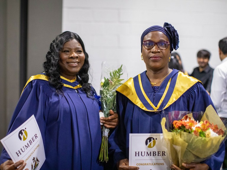 two graduates holding flowers