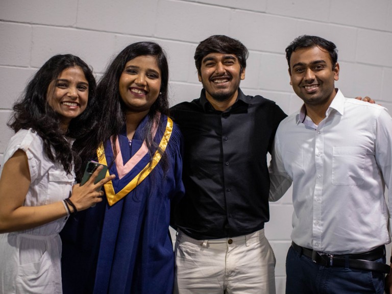 graduate posing with three ceremony guests