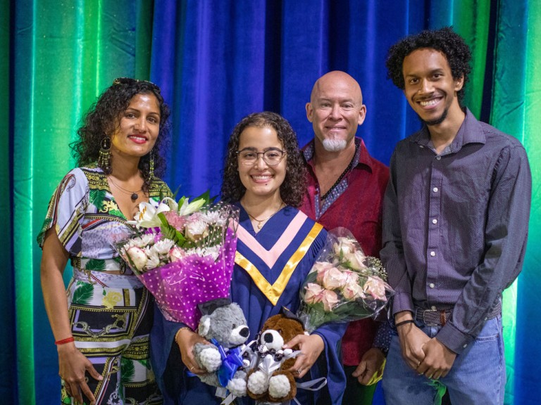 graduate holding flowers poses with family