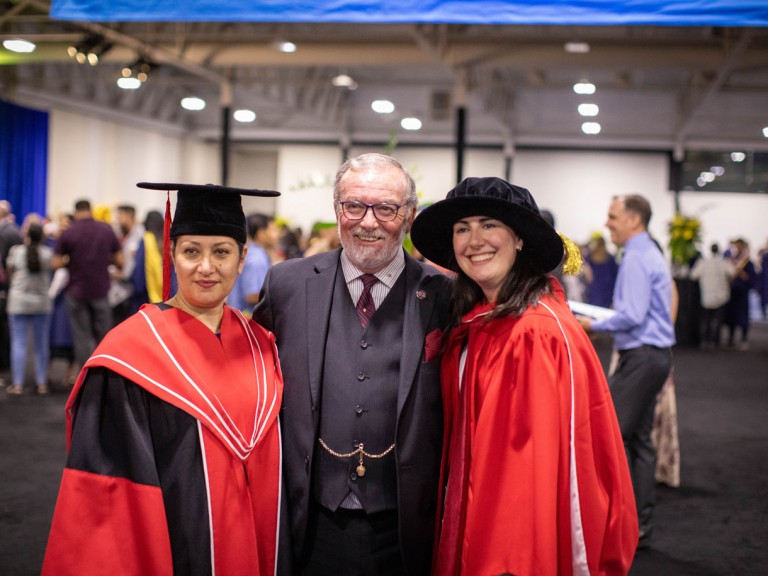 Three people in formalwear pose for photo