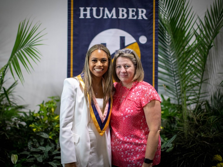 Graduate wearing stole collar poses with ceremony guest