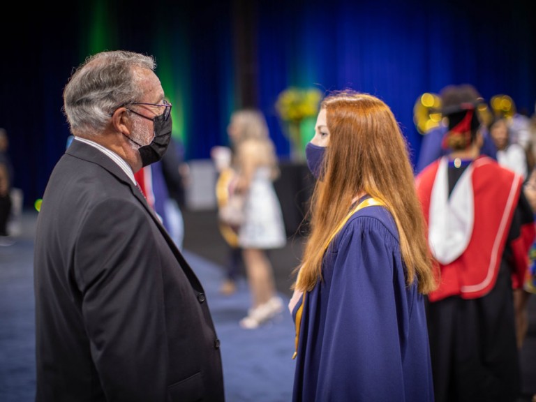 Humber graduate talking to person in suit with face masks on