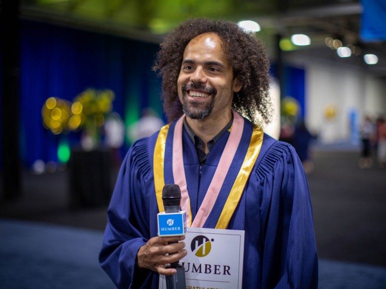 Humber graduate smiling holding a microphone
