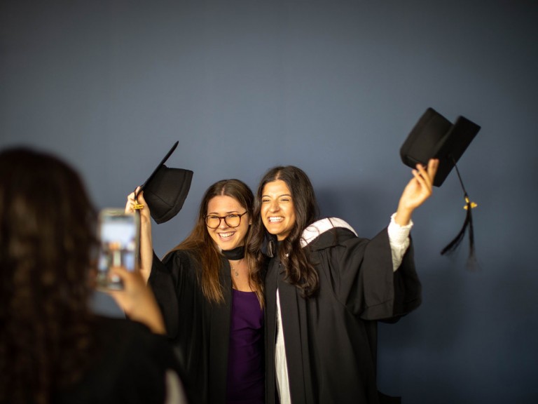 two graduates remove their caps for photo