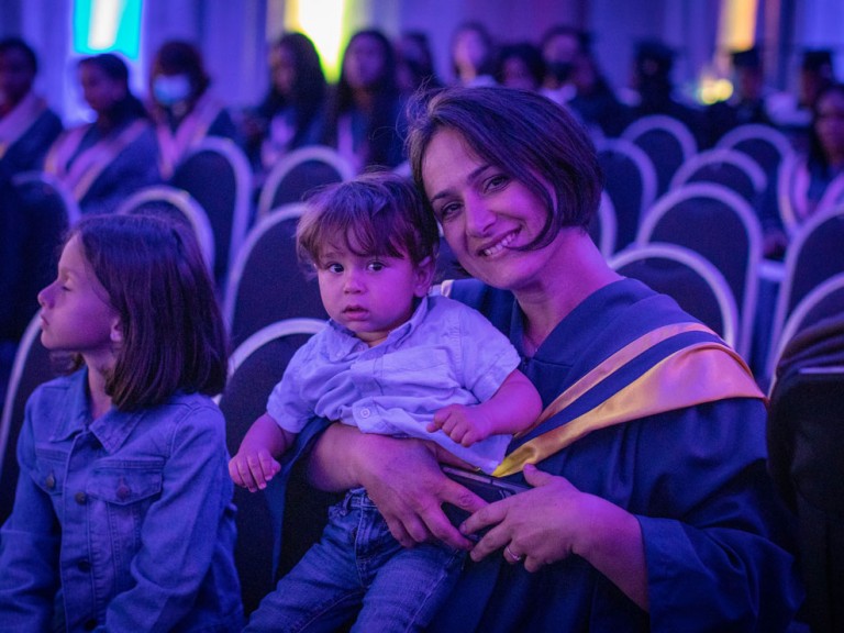 Humber graduate smiles in seat with their young children