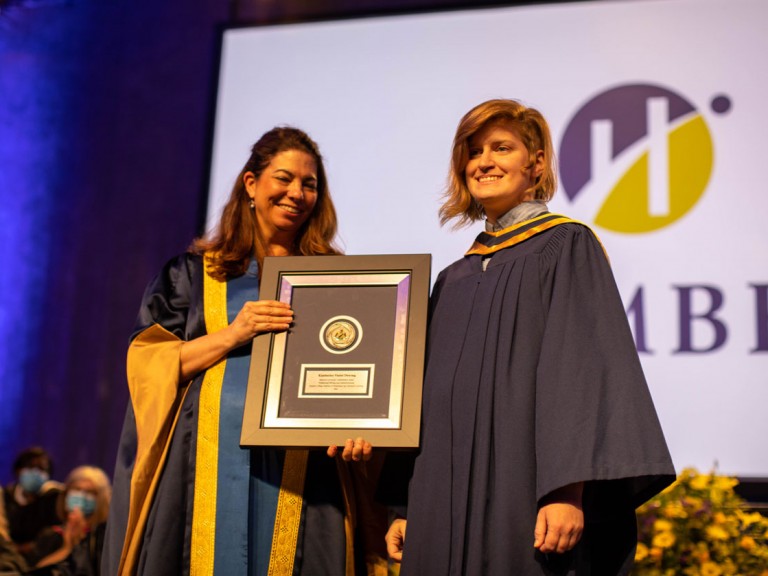 Humber graduate presented with framed document on stage