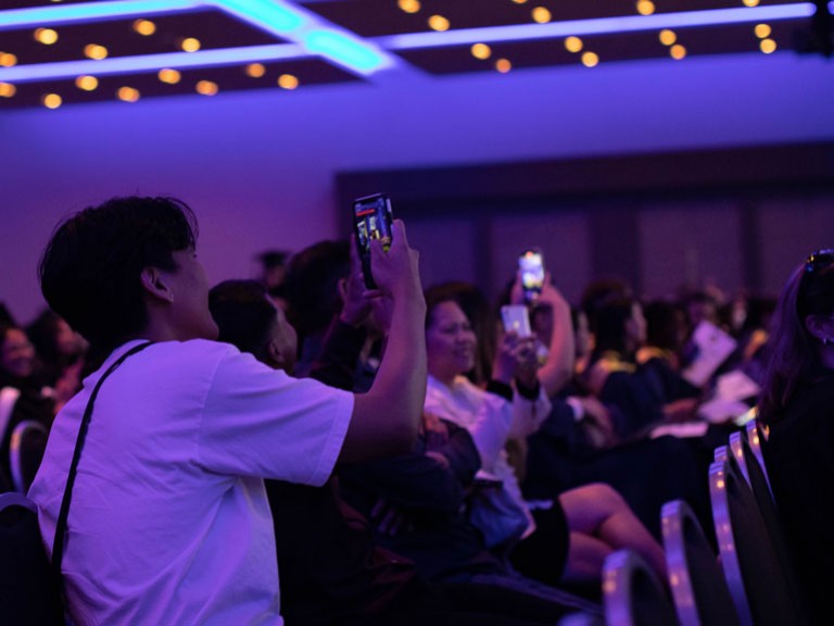 Audience members hold up cell phones