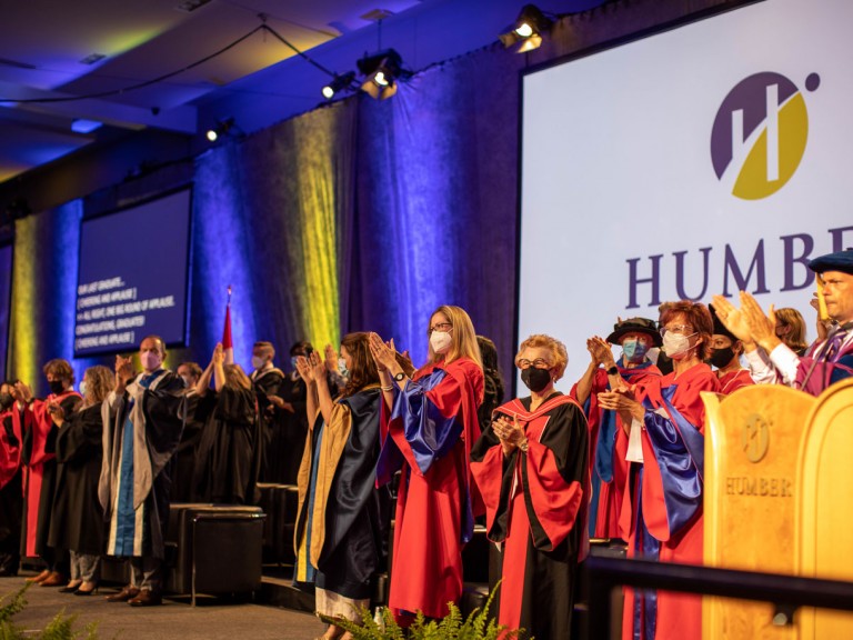 Faculty on stage standing and clapping