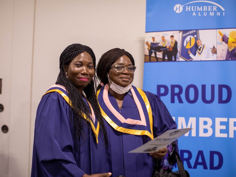 two graduates pose for camera