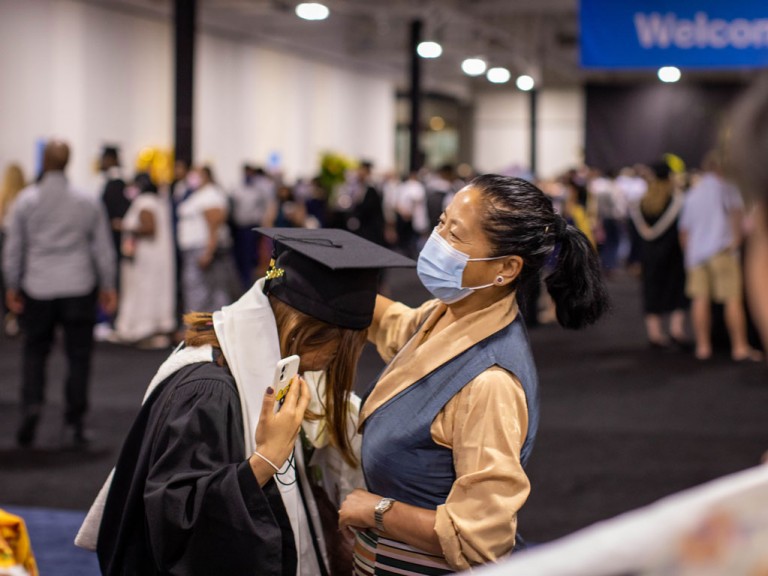graduate wearing black cap leaning towards family member