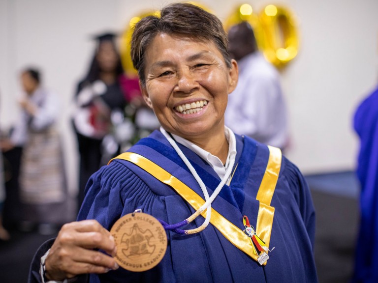Humber Indigenous graduate proudly holds up their badge
