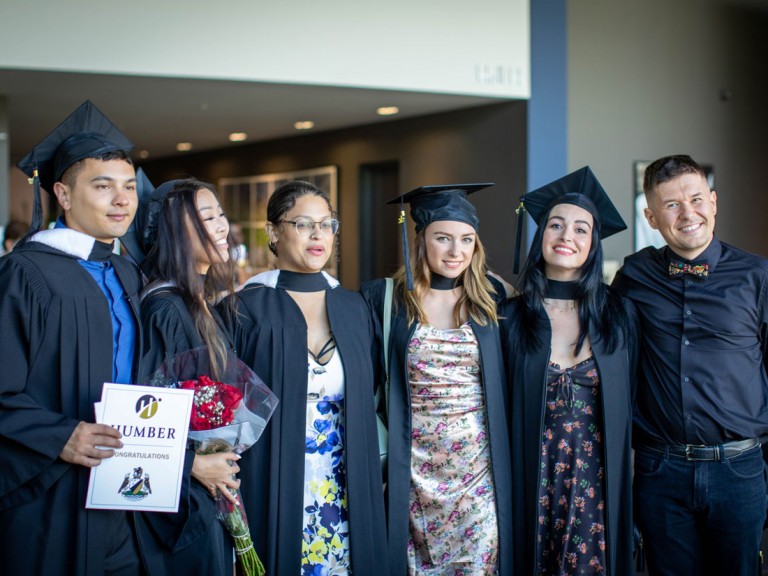 Graduates wearing black caps and gowns pose together