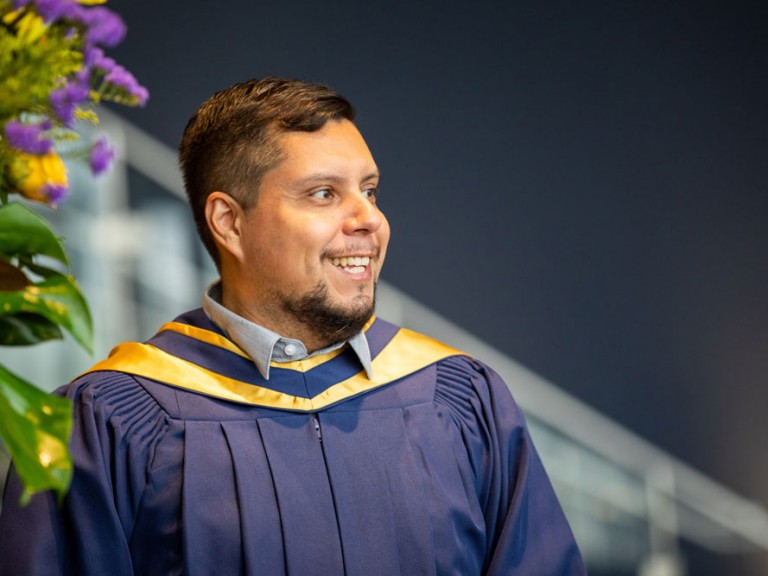 Person in graduate robe smiling