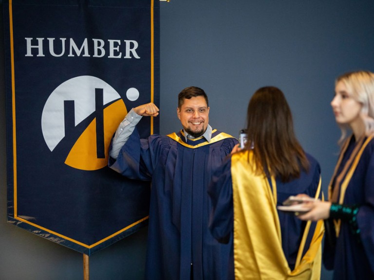 Grads taking pictures of each other with Humber banner