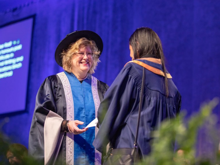 Ann Marie Vaughn smiling at graduate on stage