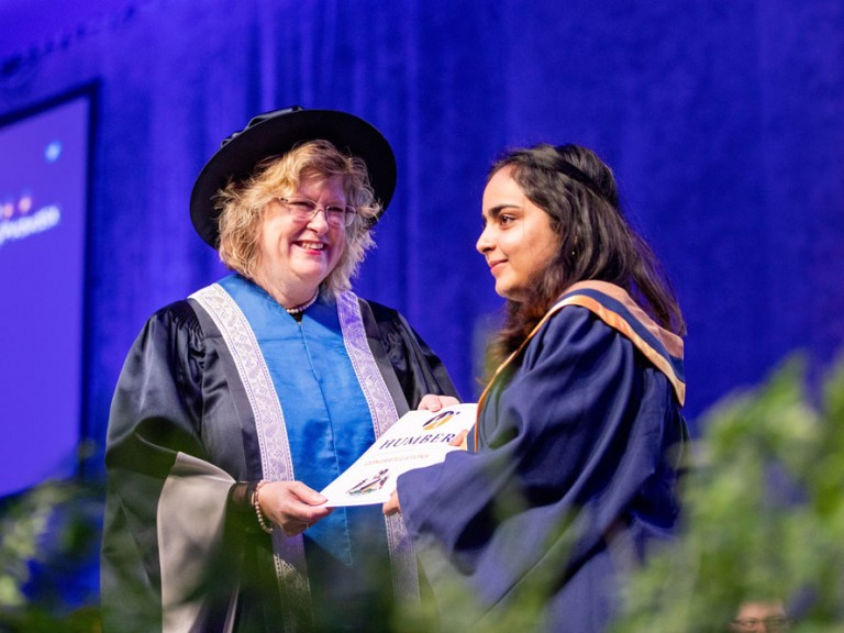 Ann Marie Vaughn presenting certificate to graduate on stage