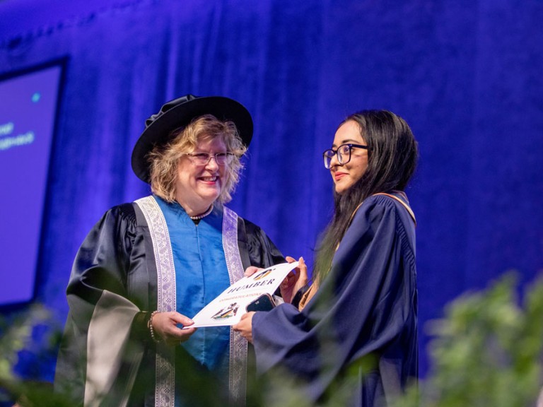 Ann Marie Vaughn presenting certificate to graduate on stage