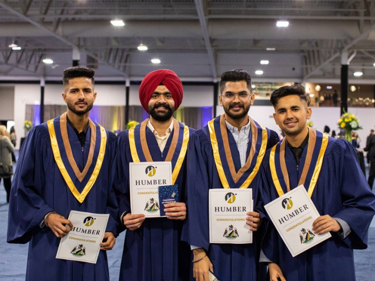 Four graduates posing with their certificates