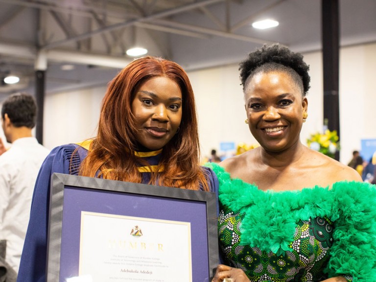 Grad posing with framed award beside family member