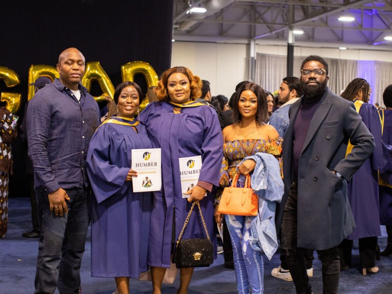 Two grads posing with three others