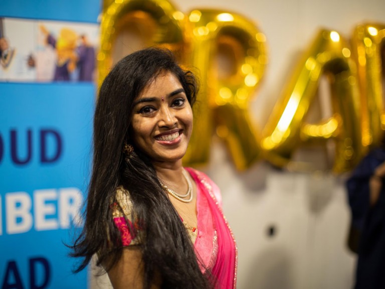 Person smiling with GRAD balloons in background