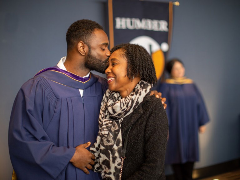 Grad kissing family member on their head