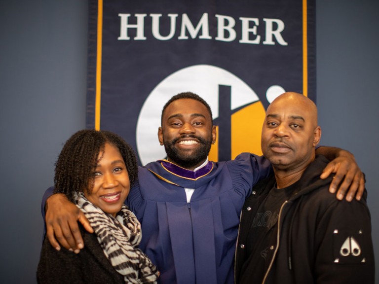 Grad with parents in front of Humber banner