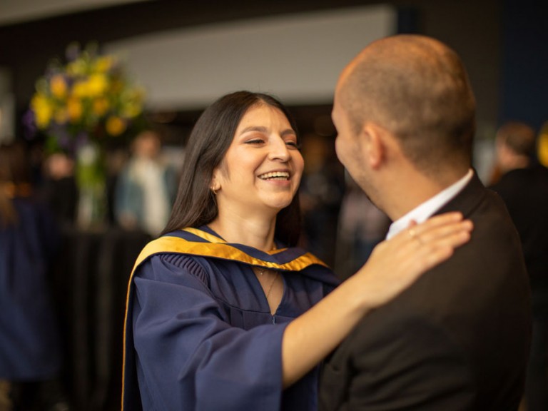 Grad hugging and smiling someone