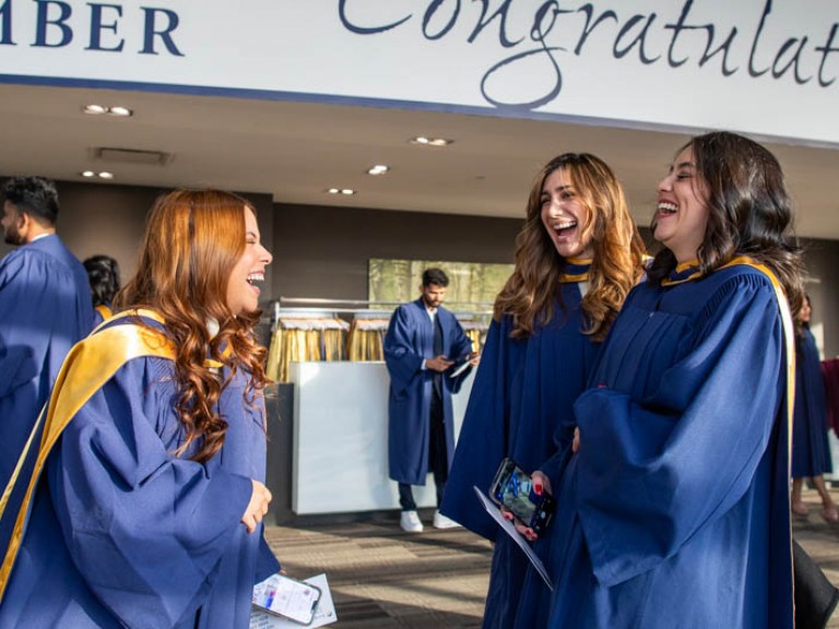 Three graduates laughing together