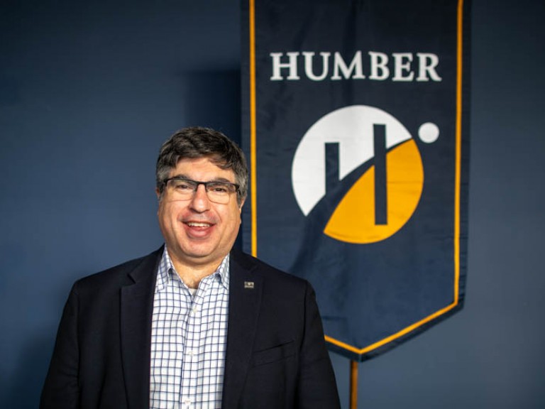 Person poses for photo in front of Humber flag