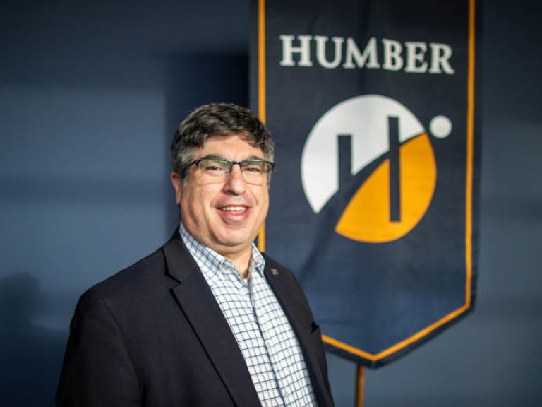 Person poses for photo in front of Humber flag