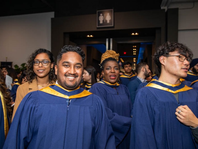 Graduates in ceremony hall smile for camera