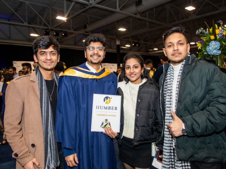 Graduate poses with three ceremony guests for photo