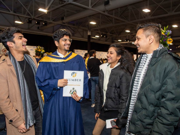 Graduate laughing with three ceremony guests