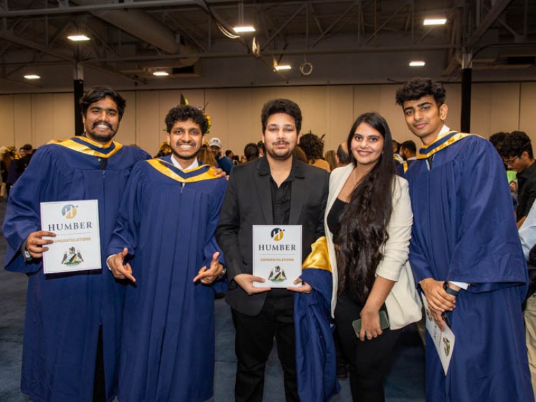 Three graduates pose with two guests for photo