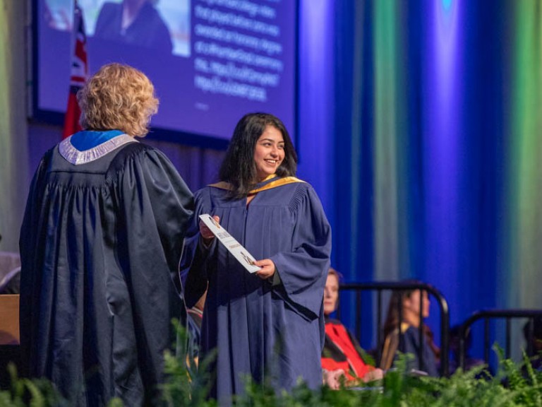 Graduate on stage smiling towards audience