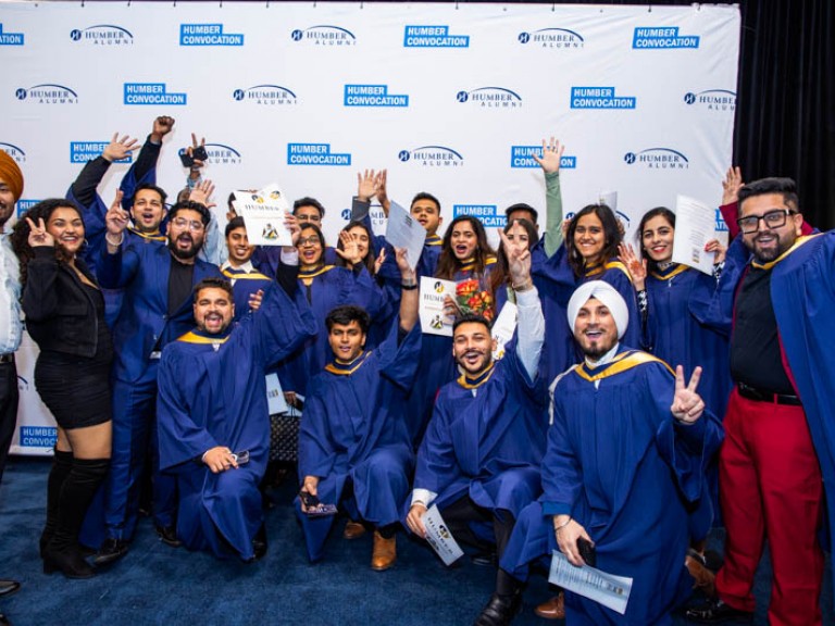 Large group of graduates raise their arms in celebration for photo