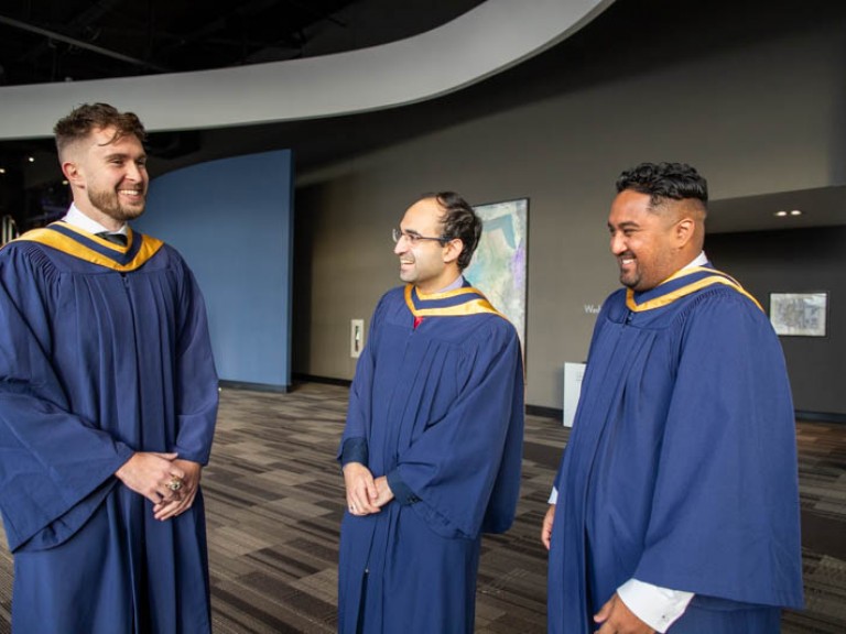 Three graduates standing and smiling