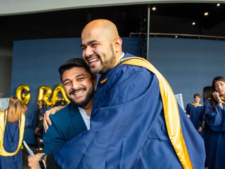 Graduate hugs someone as they both smile