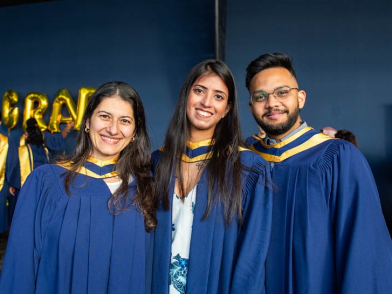 Three graduates smile for camera